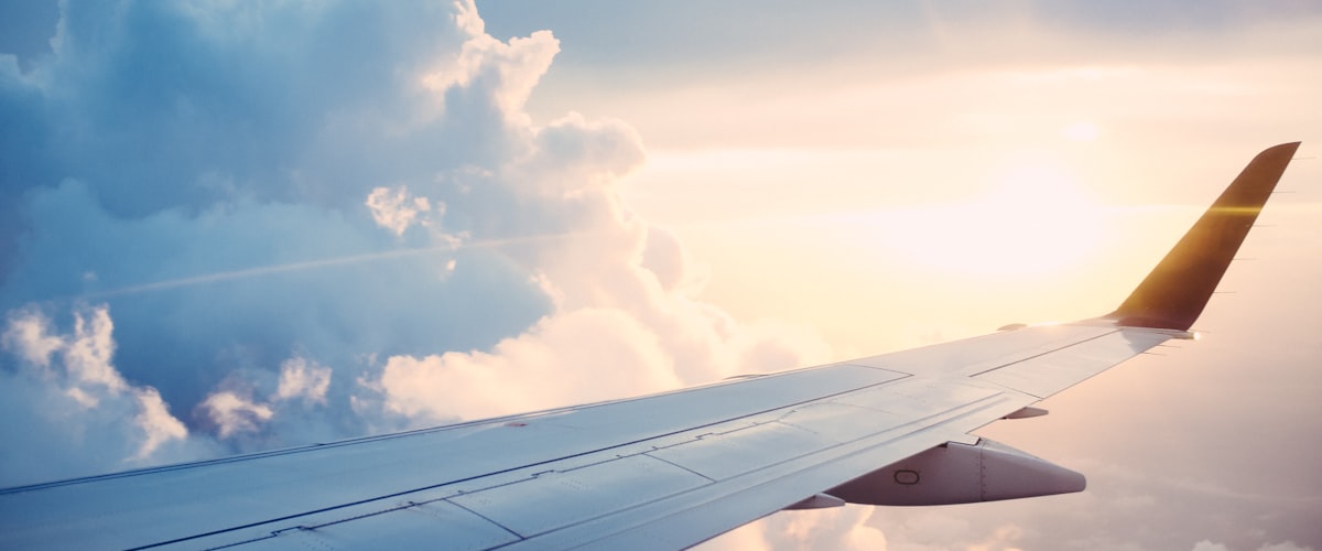 Aeroplane wing above the clouds - travel vaccinations and travel health advice at Barons Court Pharmacy